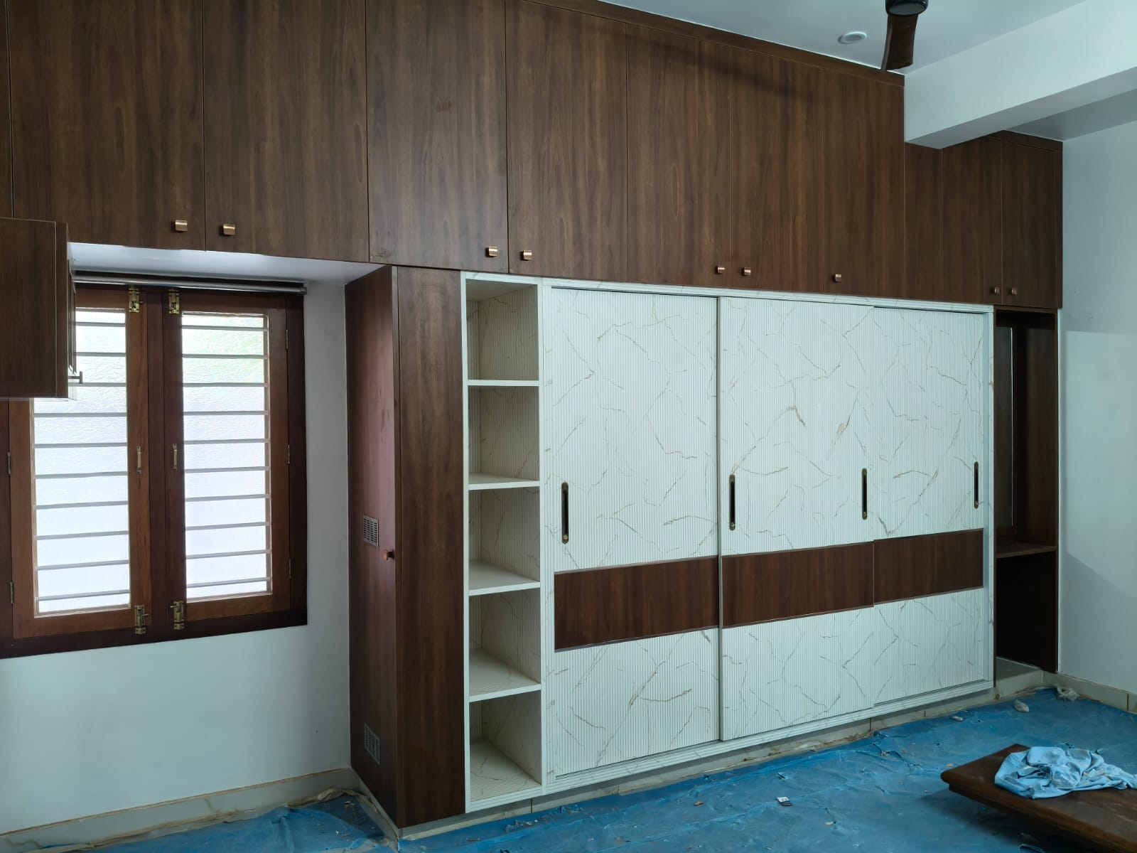 Full-height residential wardrobe with timber cabinetry, light sliding fronts, and open side shelves