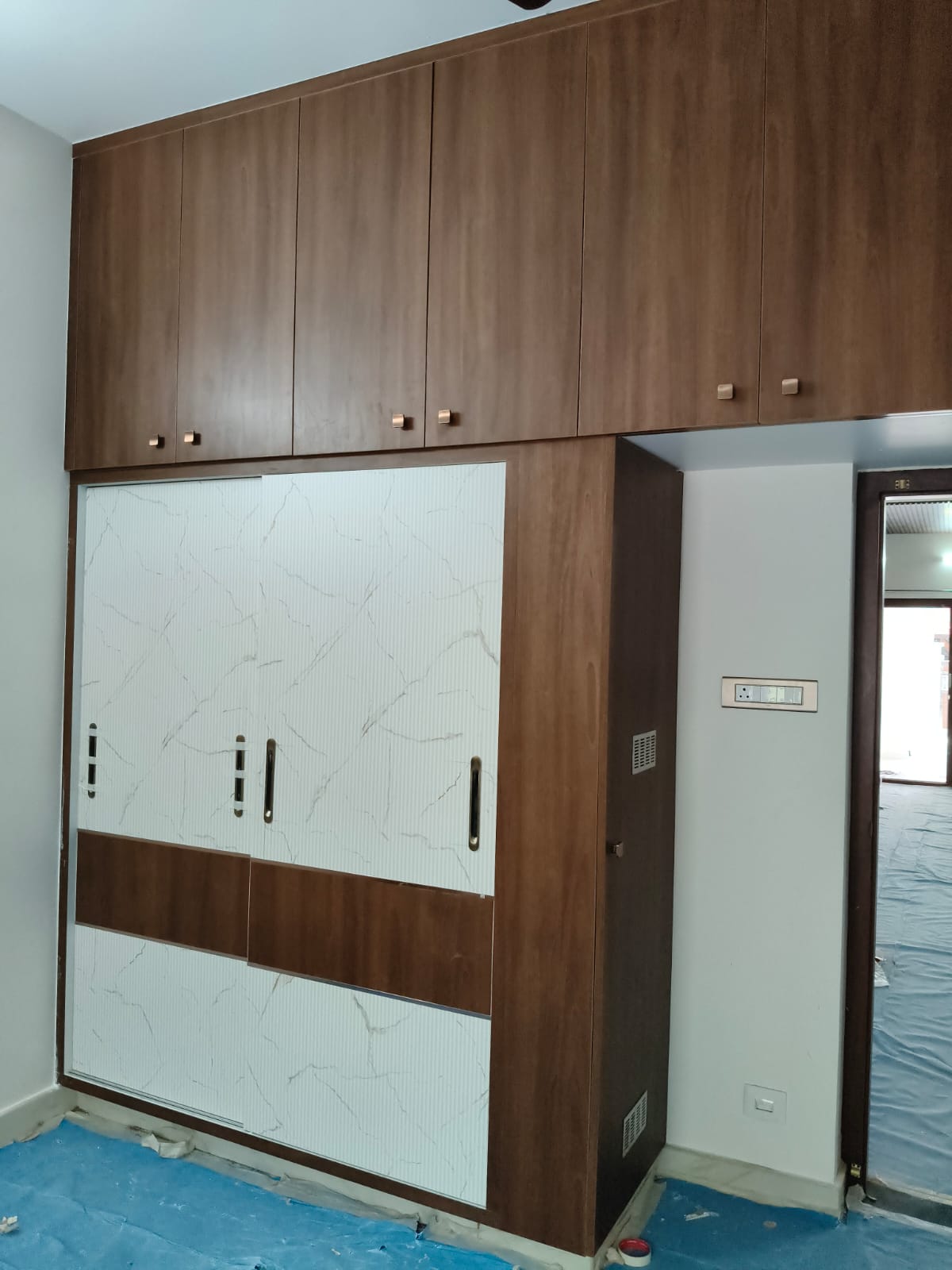 Compact fitted wardrobe combining timber cabinetry and light patterned sliding doors