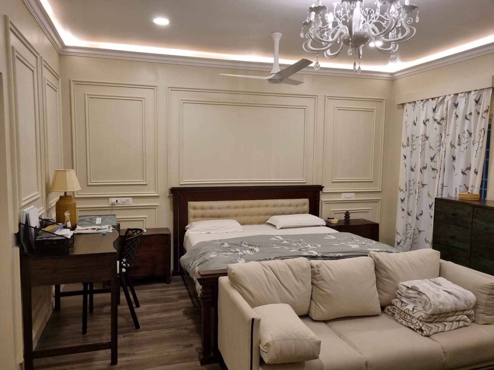 Completed sleeping area with timber bed, desk, sofa, and decorative wall panels