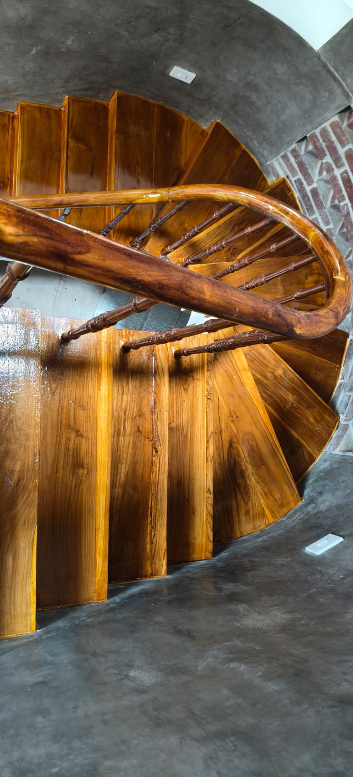 Close view of polished timber treads, turned balusters, and curved handrail