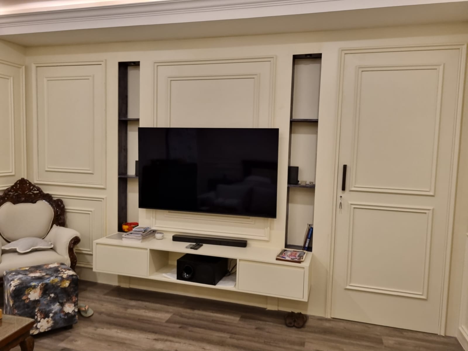 Custom bedroom media wall with integrated doors, display niches, and floating console